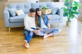 Young couple sitting on the floor of new home using computer laptop and smiling happy for moving to a new home Royalty Free Stock Photo