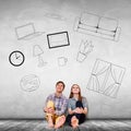 Young couple sitting on the floor among painted furniture on the wall. Royalty Free Stock Photo