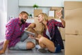 Young couple sitting on the floor with tablet pc and choosing furniture to their new apartment.