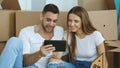 Young couple sitting on floor using tablet computer after reloction in their new home Royalty Free Stock Photo