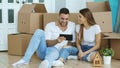 Young couple sitting on floor using tablet computer after reloction in their new home Royalty Free Stock Photo