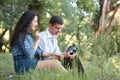 Young couple sitting on the grass in the forest and looking on sunset, listen to radio, summer nature, bright sunlight, shadows an Royalty Free Stock Photo