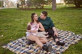 young couple sitting on the grass in the park as they feed their baby and look at each other Royalty Free Stock Photo