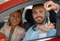 Young couple sitting inside new car and holding keys to it. Concept for car rental Royalty Free Stock Photo