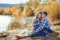 A young couple is sitting by the lake at sunset with a Husky breed dog. Royalty Free Stock Photo