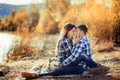 A young couple is sitting by the lake at sunset with a Husky breed dog. Royalty Free Stock Photo