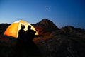 Young Couple Sitting near Illuminated Tent and Looking at Each Other at Beautirul Evening in the Mountains