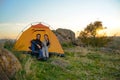 Young Couple Sitting near Tent at Beautirul Evening in the Mountains. Adventure and Family Travel.