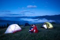 Young couple sitting near tent campus on background of mountain landscape Royalty Free Stock Photo