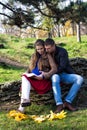 Young couple sitting in the park and reading. Royalty Free Stock Photo