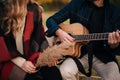 Young couple sitting and playing to the guitar on a field. Royalty Free Stock Photo