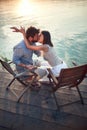 Young couple sitting by the sea, hugging and kissing Royalty Free Stock Photo