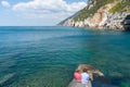 Young couple sitting on rocks on edge of Ligurian Sea at Portovenere looking out at view. and medieval ruins Royalty Free Stock Photo