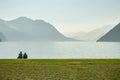 Young couple sitting on shores of Lake Luzern in small park in Brunnen