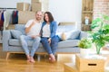 Young couple sitting on the sofa arround cardboard boxes moving to a new house showing and pointing up with finger number one Royalty Free Stock Photo