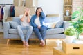 Young couple sitting on the sofa arround cardboard boxes moving to a new house suffering from headache desperate and stressed Royalty Free Stock Photo