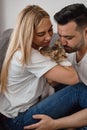 Young couple sitting at sofa and cuddling a small cat Royalty Free Stock Photo