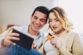 Young couple sitting on sofa and doing online shopping Royalty Free Stock Photo