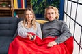Young couple sitting on the sofa at home looking positive and happy standing and smiling with a confident smile showing teeth Royalty Free Stock Photo