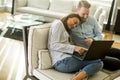 Young couple sitting on a sofa and, using laptoped atmo