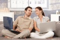 Young couple sitting on sofa using laptop smiling Royalty Free Stock Photo