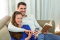 Young couple sitting on sofa and using mobile phone Royalty Free Stock Photo