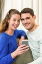 Young couple sitting on sofa and using mobile phone Royalty Free Stock Photo