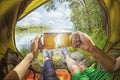 Young couple sitting in the tent and drinking tea while looking on the Desna river