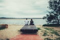 Young couple sitting together on a bench and looking at the river. Back view Royalty Free Stock Photo