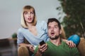 Couple sitting together on a sofa at home watching television, joyfully smiling enjoying a night in together Royalty Free Stock Photo