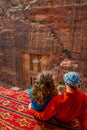 Young couple sitting at a viewpoint on Al Khazneh tomb also called Treasury at Petra, Jordan