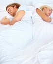 At odds with one another. A young couple sleeping back to back in bed. Royalty Free Stock Photo