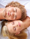 Rest and relaxation. A young couple sleeping in bed with their heads together. Royalty Free Stock Photo