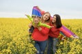 A young couple with a small child and an LGBT flag in a field with yellow rapeseed flowers are laughing merrily. Royalty Free Stock Photo