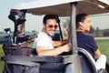 Couple smiling and driving in buggy in golf course Royalty Free Stock Photo