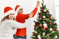 Young couple smiling happy decorating christmas tree at home