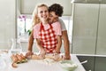 Young couple smiling happy kneading dough with hands at kitchen Royalty Free Stock Photo