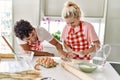 Young couple smiling happy kneading dough with hands at kitchen Royalty Free Stock Photo