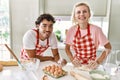 Young couple smiling happy kneading dough with hands at kitchen Royalty Free Stock Photo