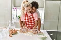 Young couple smiling happy kneading dough with hands at kitchen Royalty Free Stock Photo
