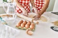 Young couple smiling happy kneading dough with hands at kitchen Royalty Free Stock Photo