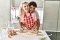 Young couple smiling happy kneading dough with hands at kitchen Royalty Free Stock Photo