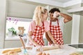 Young couple smiling happy kneading dough with hands at kitchen Royalty Free Stock Photo