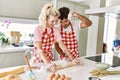 Young couple smiling happy kneading dough with hands at kitchen Royalty Free Stock Photo