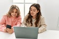 Young couple smiling happy working using laptop and smartphone at home Royalty Free Stock Photo