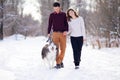 Young couple smiling and having fun in winter park with their husky dog Royalty Free Stock Photo