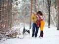 Young couple smiling and having fun in winter park with their husky dog Royalty Free Stock Photo