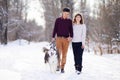 Young couple smiling and having fun in winter park with their husky dog Royalty Free Stock Photo