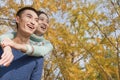 Young couple smiling and piggyback in park in autumn Royalty Free Stock Photo