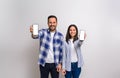 Young couple smiling and showing blank screens of smart phones for advertisements. Cheerful man and woman promoting cellphones